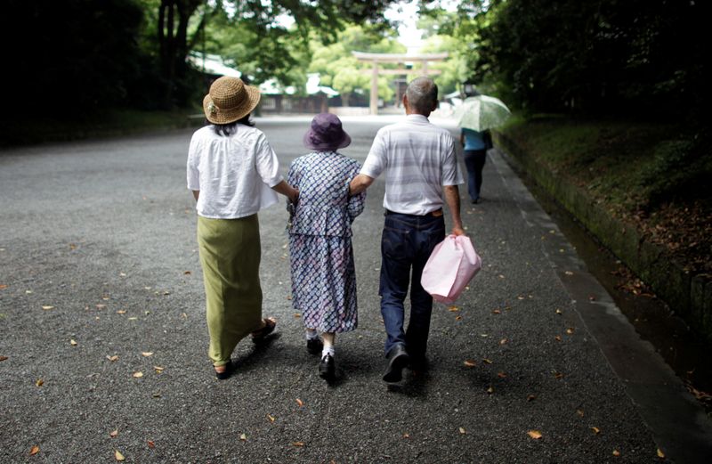 FILE PHOTO: An elderly woman is led to a temple