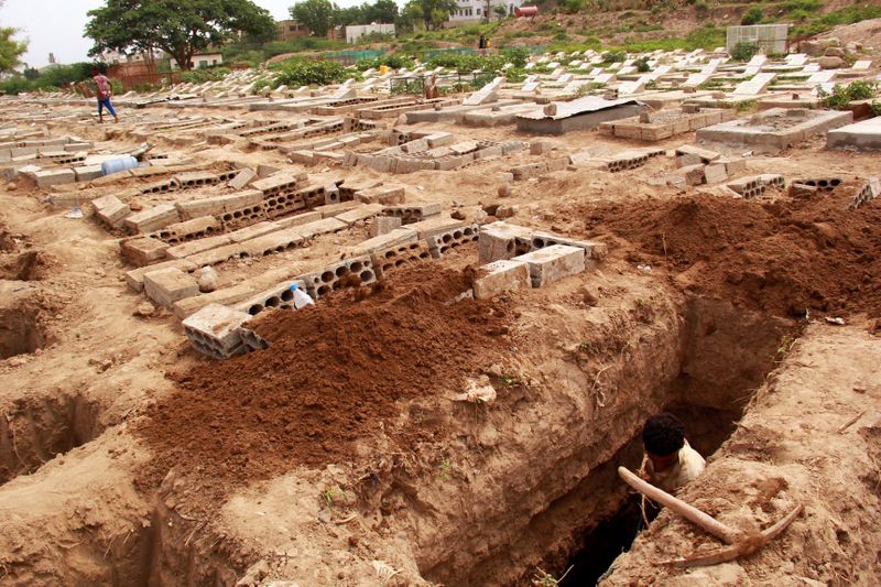 FILE PHOTO: A man digs a grave at a cemetery