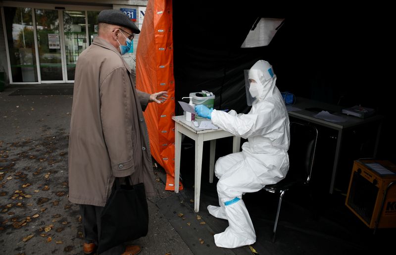 A health worker in protective suit gives a document to