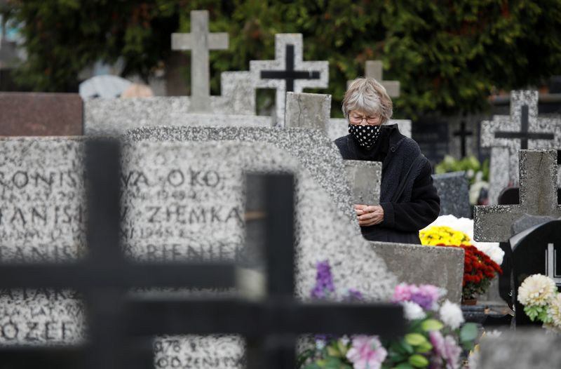 A woman wearing a protective mask visits a relatives’ grave