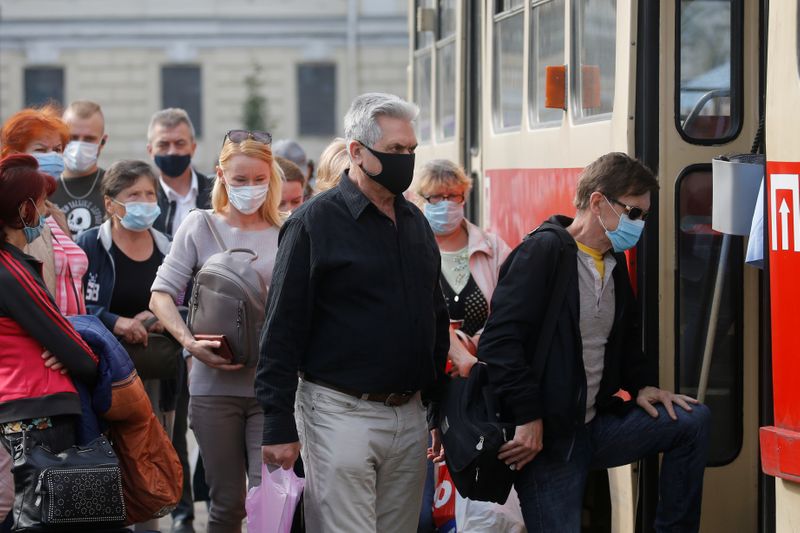 People wearing protective face masks get on a tram in