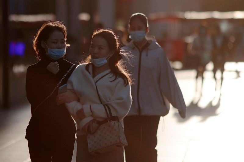 Women wearing face masks walk at a main shopping area