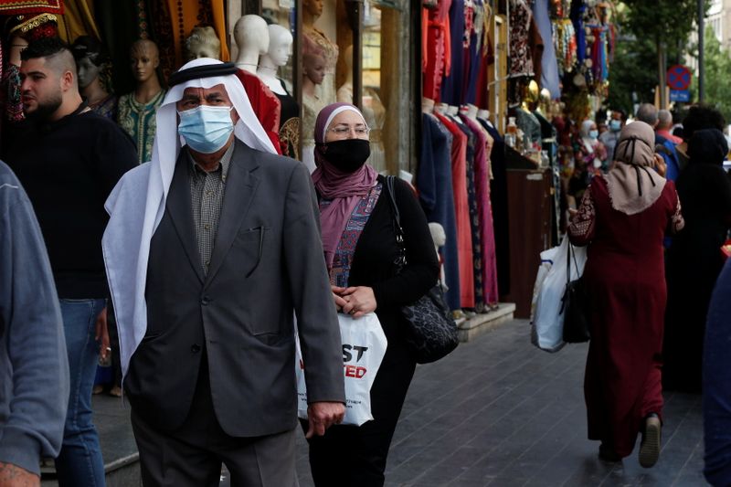 People, some wearing protective masks, walk in downtown Amman, amid