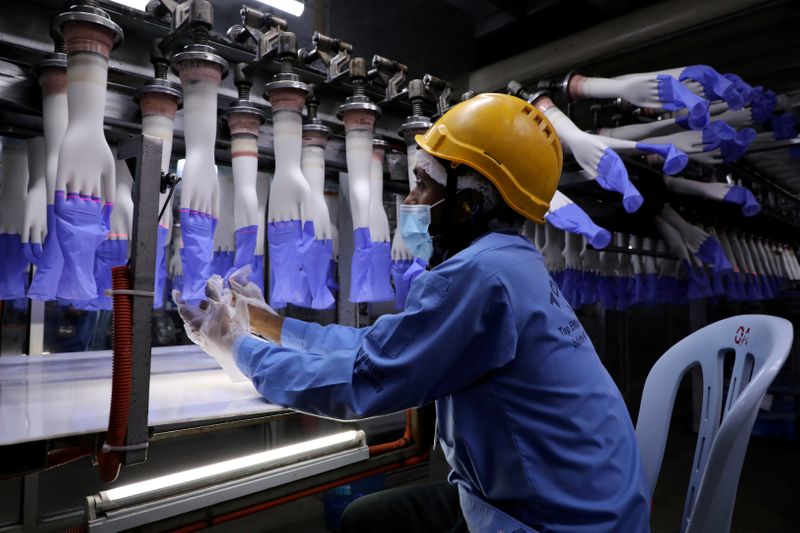FILE PHOTO: A worker inspects newly-made gloves at Top Glove