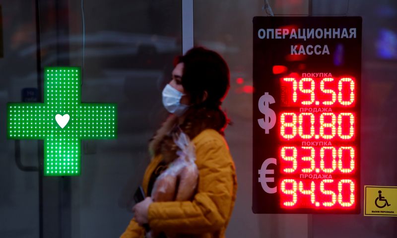 FILE PHOTO: Woman walks past a board showing currency exchange