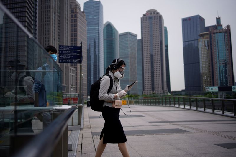 People wearing protective face masks walk past office buildings in