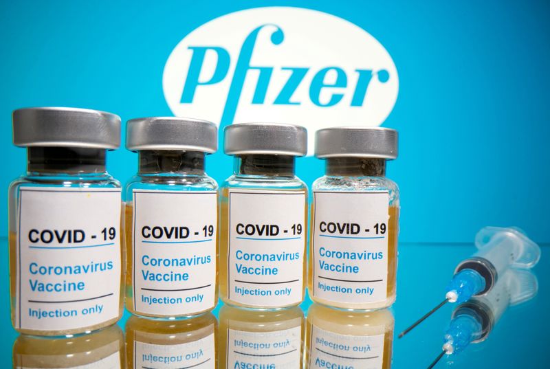 Vials and medical syringe are seen in front of Pfizer