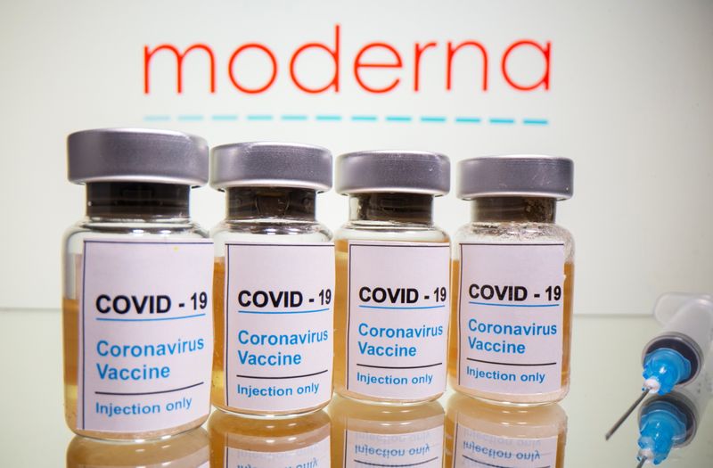 Vials and medical syringe are seen in front of Moderna