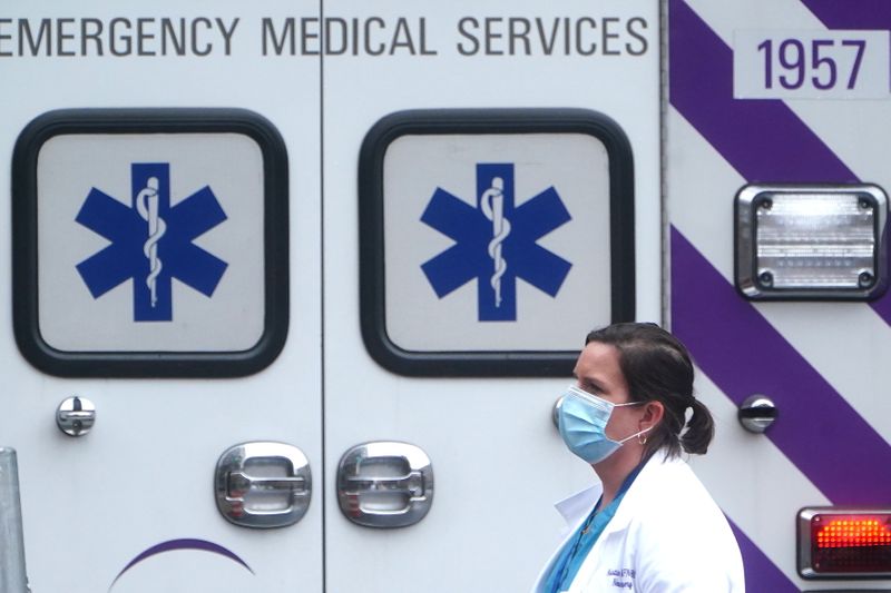 A health care professional walks past an ambulance during the