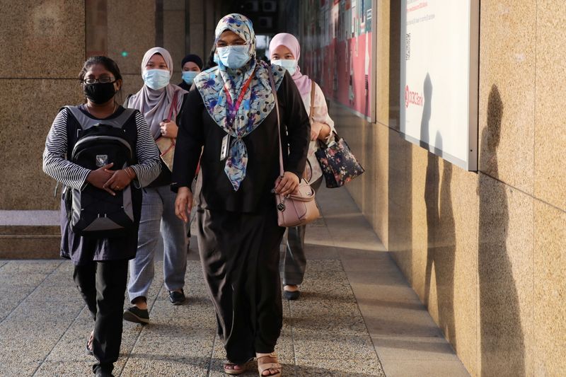 FILE PHOTO: People wearing protective masks walk on a street,