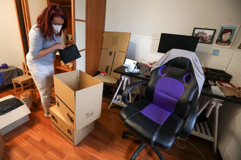Ines Alcolea places objects inside moving boxes before leaving her