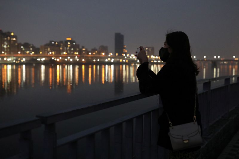 A woman takes photo of the sunset at a riverside,