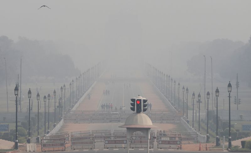 People walk near India Gate on a smoggy afternoon in