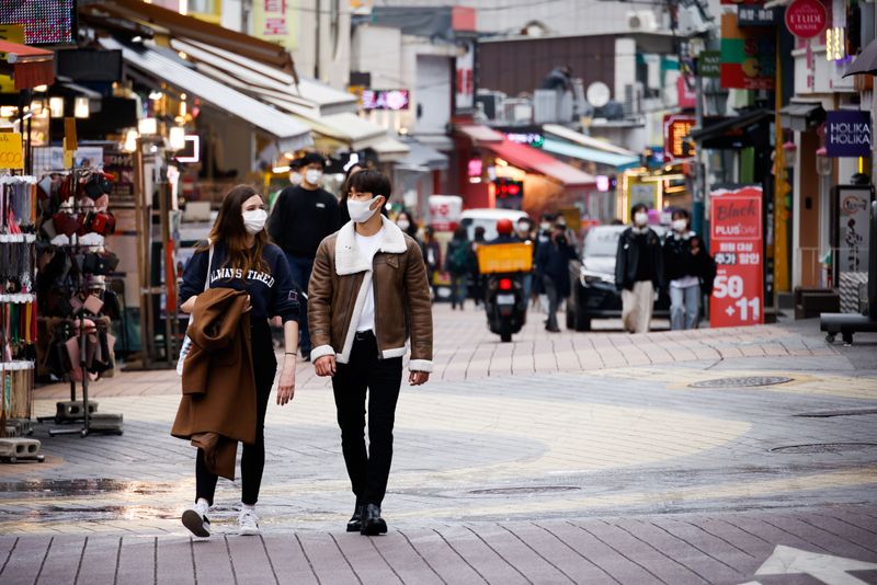 Pedestrians wearing masks walk on a shopping street amid the