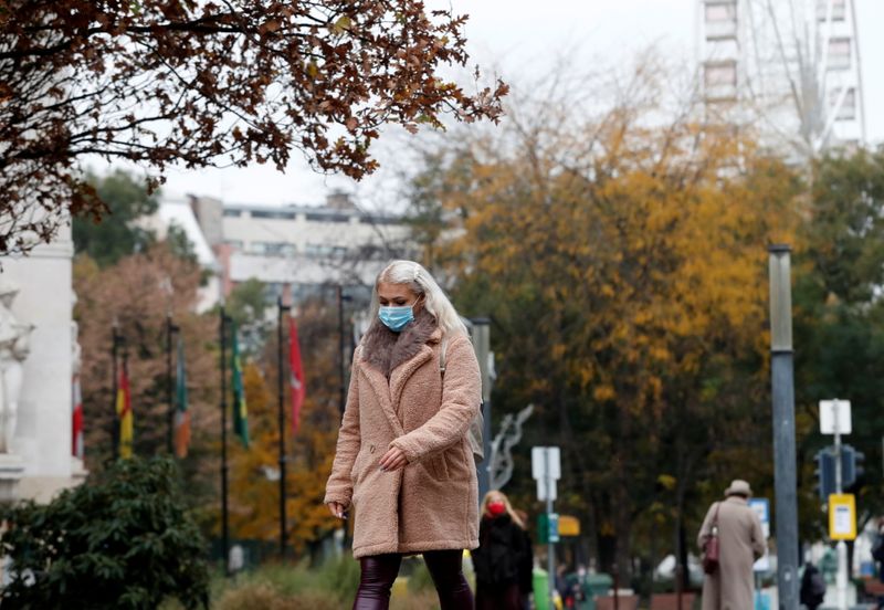 A woman wearing a protective face mask walks in downtown
