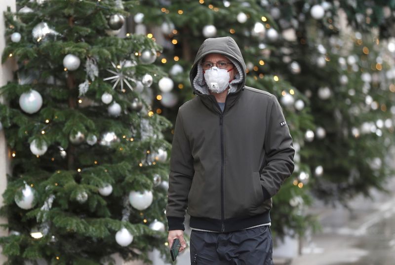 A man walks past Christmas decorations outside a store amid