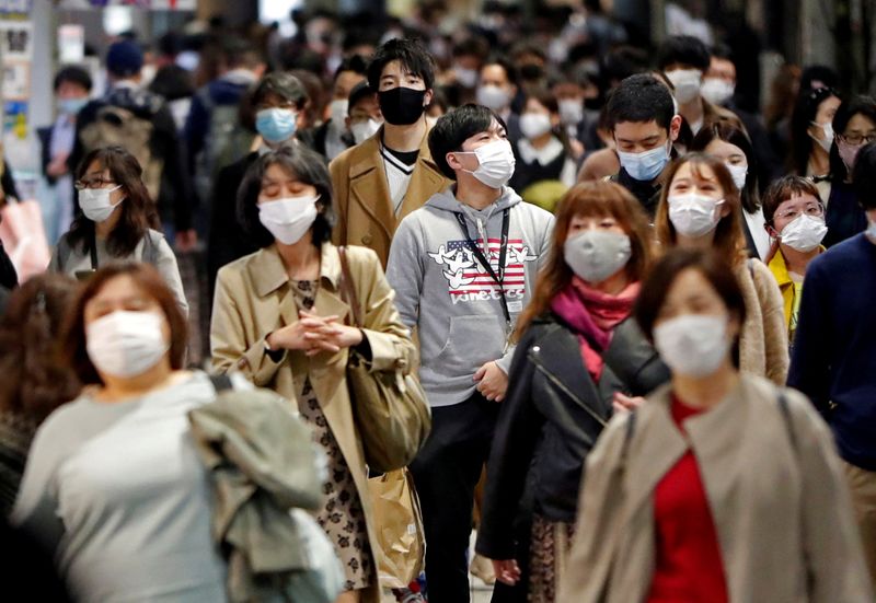 FILE PHOTO: People wearing protective face masks walk on the