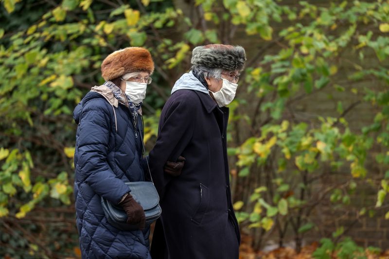 Pensioners wearing face masks and winter hats walk during lockdown