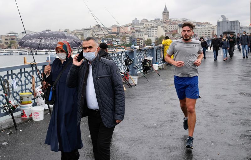 FILE PHOTO: People wearing protective masks walk over the Galata