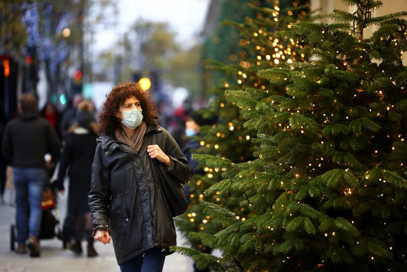 A woman walks past Christmas trees on Oxford Street, amid