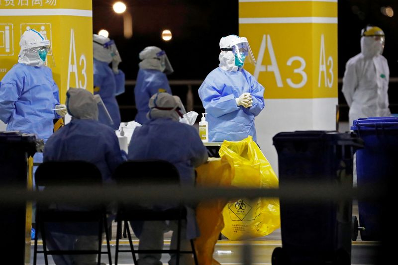 Workers in protective suits are seen at a makeshift nucleic