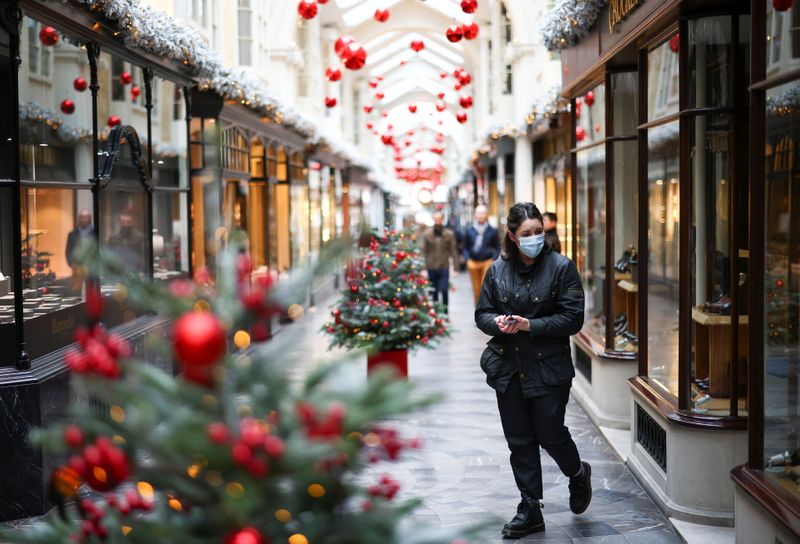 Woman walks through the Burlington Arcade adorned with Christmas decorations,