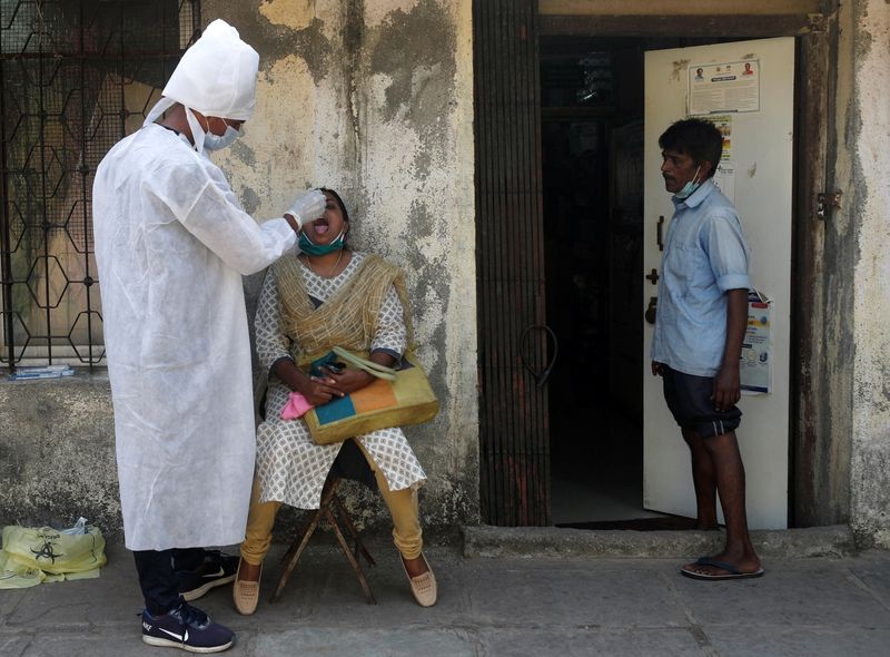 A health worker in personal protective equipment (PPE) collects a