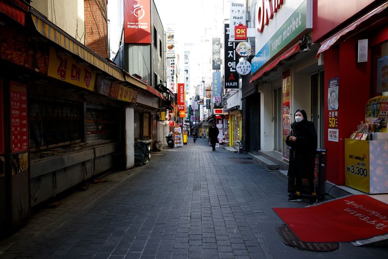 A shopkeeper waits for customers at an empty shopping district