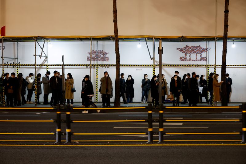 People wait for their bus at a bus stop amid