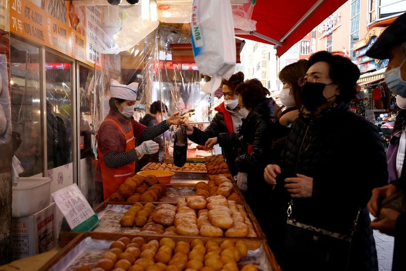 FILE PHOTO: Women buy donuts at a traditional market amid