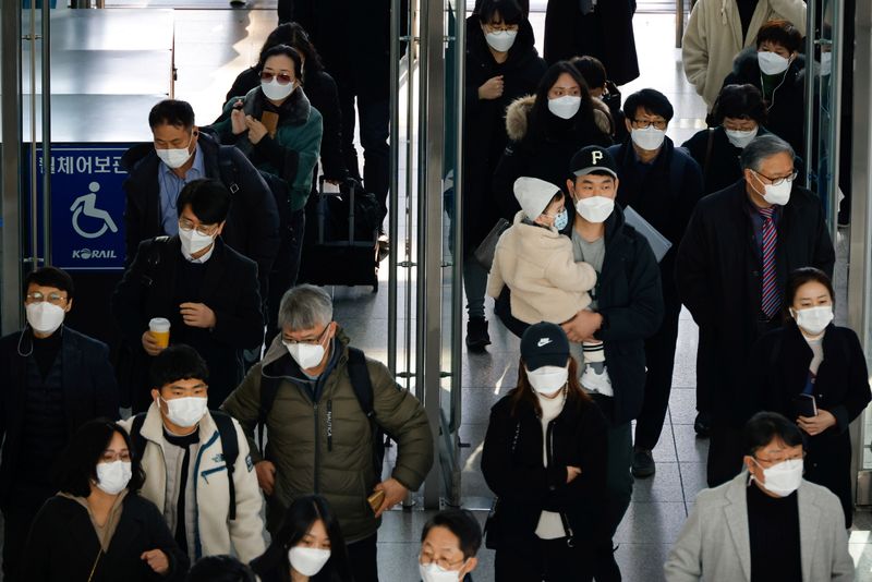 People wearing masks walk at a railway station amid the