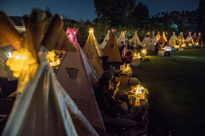 People watch movies from tents placed for social distancing at