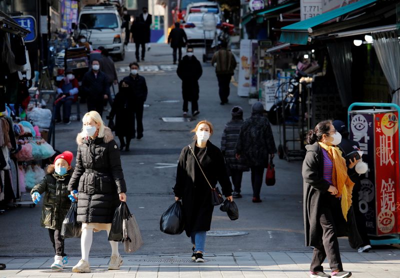 People wearing face masks walk at a traditional market amid the