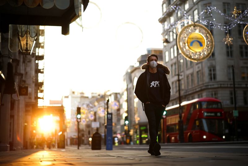 A man wearing a protective face mask walks down Strand