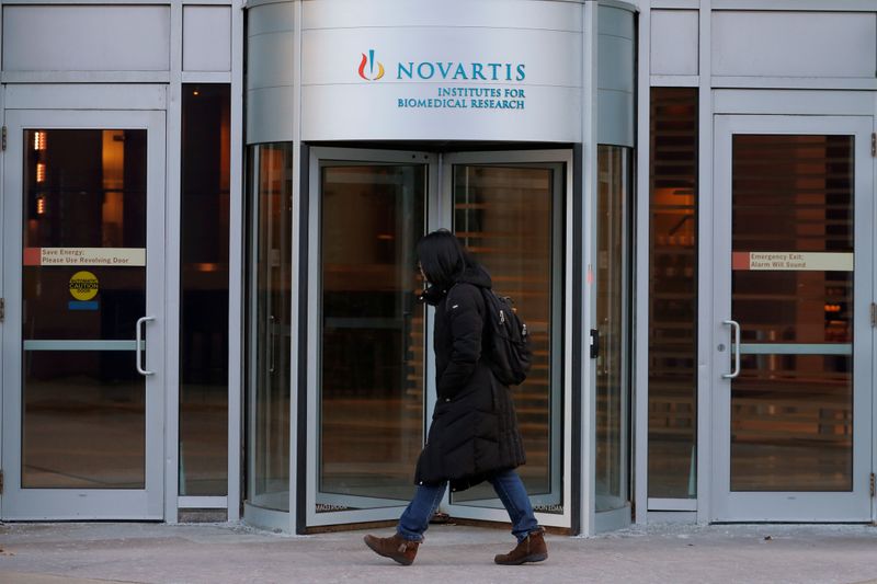 A pedestrian passes Novartis’ Institutes for Biomedical Research in Cambridge