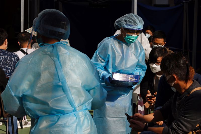 Medical workers in protective suits attend to people at a