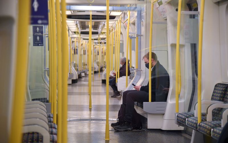 Passengers wear face masks as they sit on a tube
