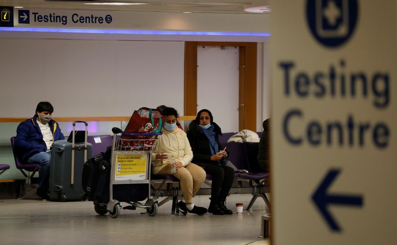 FILE PHOTO: Passengers sit beneath a testing centre sign in