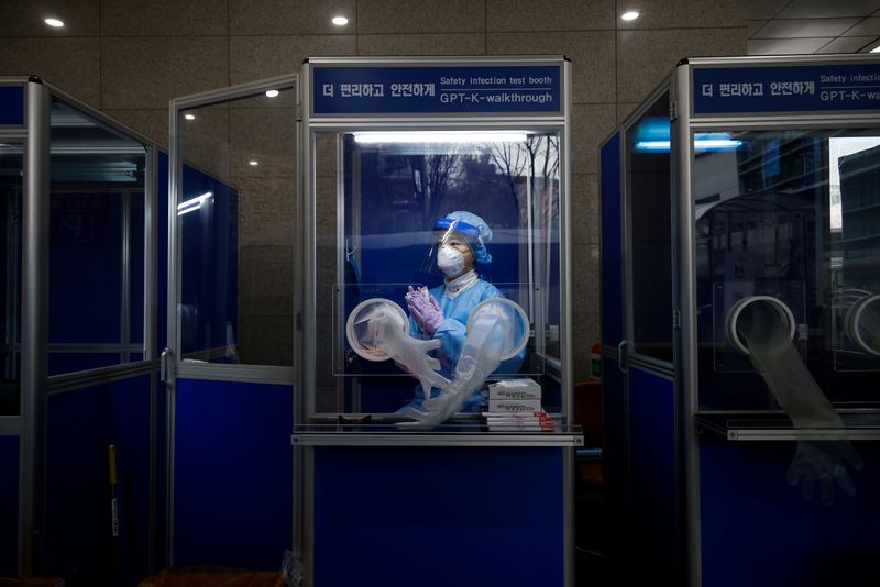 A medical worker keeps warm inside a booth as she
