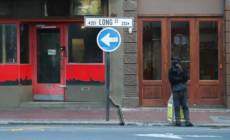 An informal car-guard stands before a closed bar and restaurant