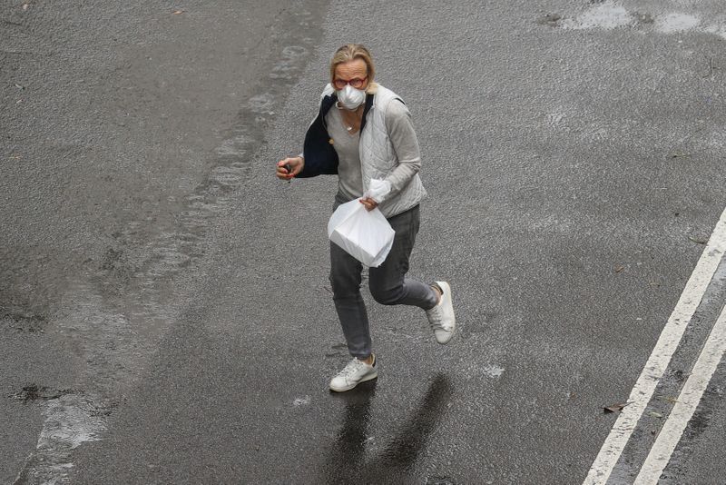 A pedestrian wears a mask while crossing a street in