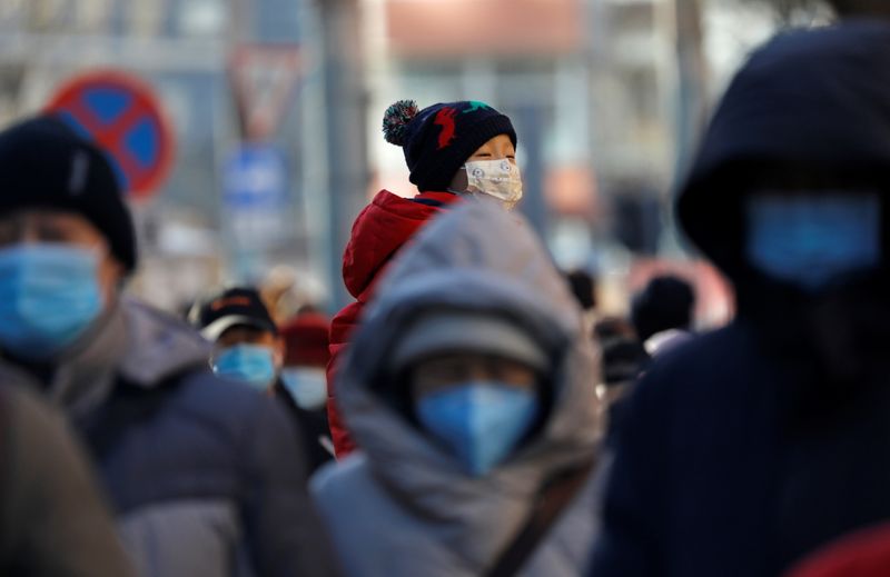 People wearing masks walk in a street in Beijing’s CBD
