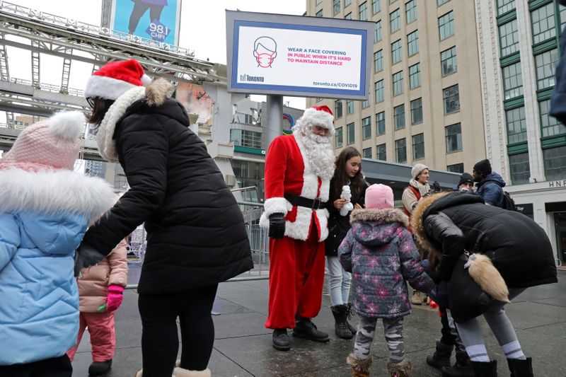 A mask-less Santa Claus poses with children from an unmasked