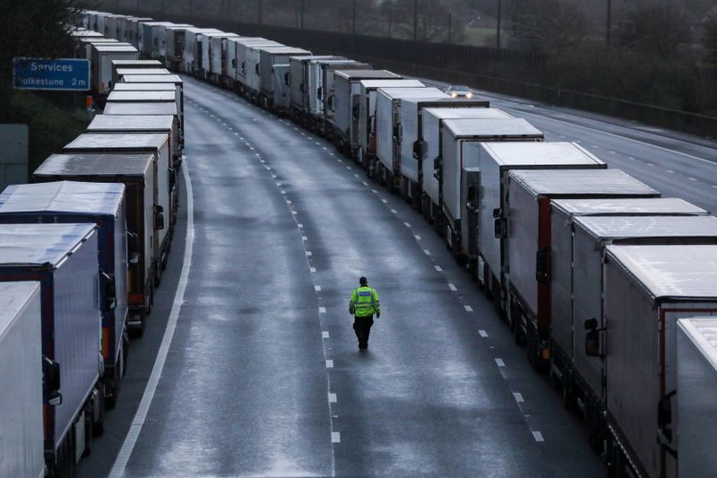 A man walks past lorries parked on the M20 motorway