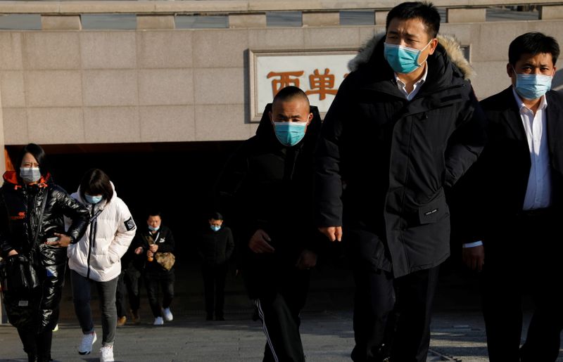 People wearing face masks walk out of a subway station