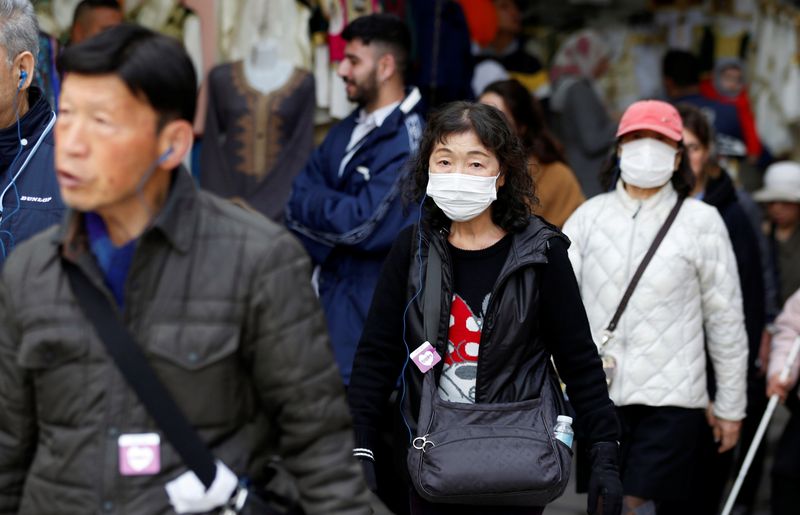 Tourists walk wearing protective face masks in the old city