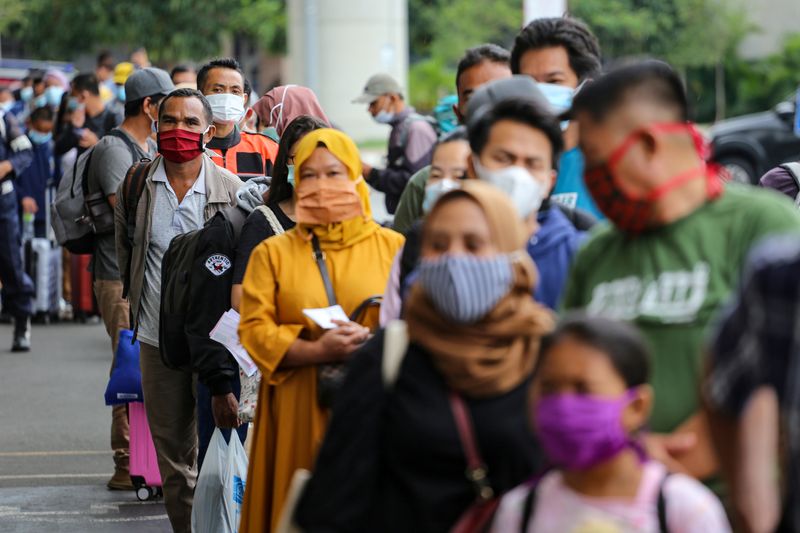 FILE PHOTO: Passengers wearing protective face masks line up to