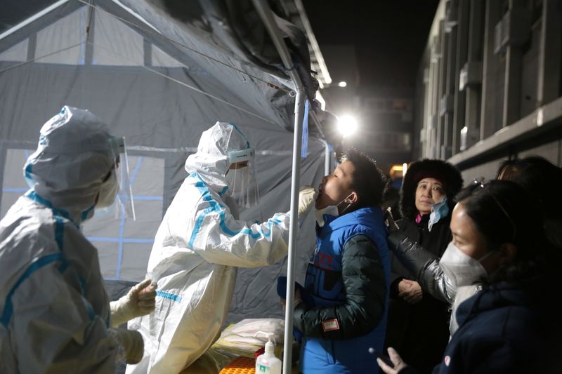 Medical worker in protective suit collects a swab from a