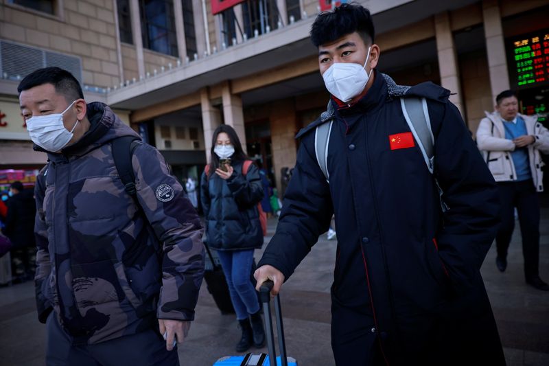 Travellers push suitcases outside Beijing Railway Station following an outbreak