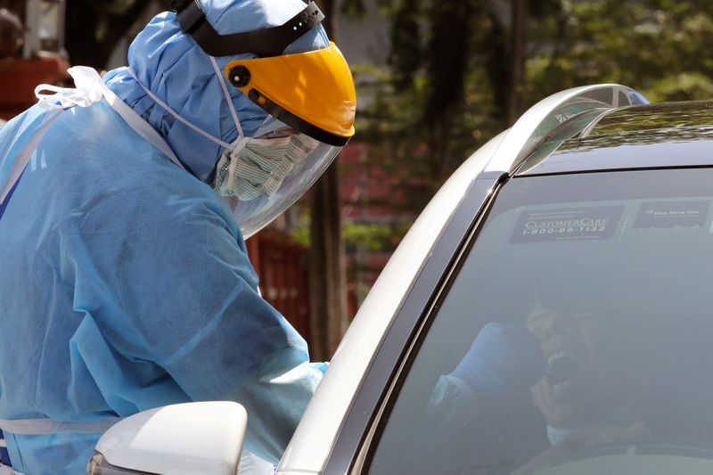 A health worker performs testing at a drive-thru coronavirus disease